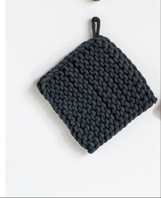 Four knitted pot holders in brown, green, black, and gray on a white background