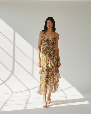 Woman in a floral dress standing outdoors with plants in the background