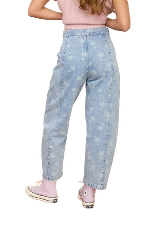 Person wearing light blue jeans and pink shoes in a room with a green couch.