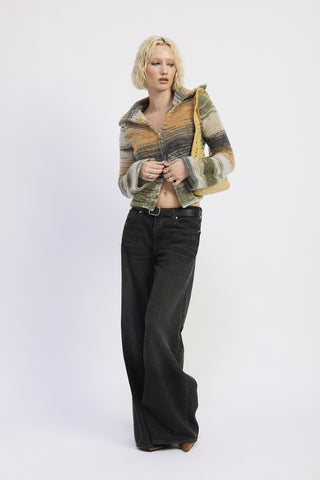 Woman wearing a patterned jacket and black pants on a white background