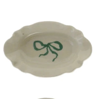 Four small ceramic dishes with colorful bow designs on a white background