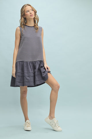Model wearing navy and white striped sleeveless drop waist dress with ruffled hem