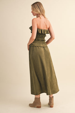 Woman wearing an olive green strapless dress on a beige background