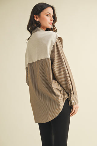 Woman wearing a beige and brown color-blocked shirt on a beige background