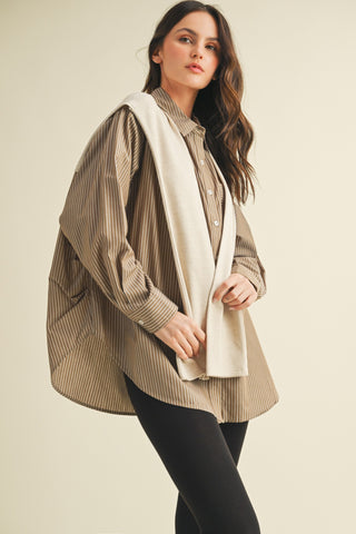 Woman wearing a beige striped shirt with a white scarf against a beige background