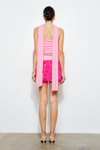 Woman wearing a pink dress with a matching cardigan on a white background