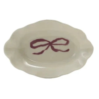 Four small ceramic dishes with colorful bow designs on a white background