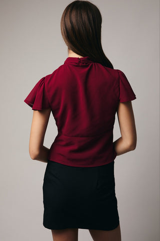 Woman wearing a red blouse and black skirt against a plain background