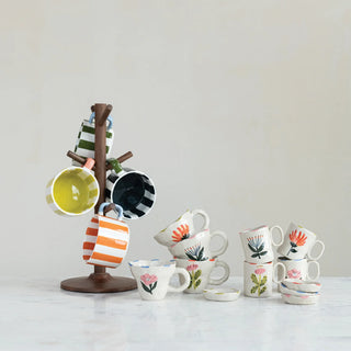 A charming collection of hand-painted stoneware mugs, featuring bold vertical stripes. Perfectly displayed on a wooden mug tree for a cozy, curated kitchen look. Dishwasher safe.