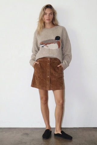 Woman wearing a sweater with a duck design and striped pants against a white background