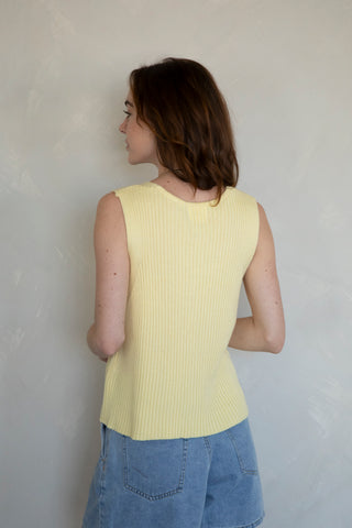 woman wearing butter yellow vinny knit vest with shorts. back view on white background. 
