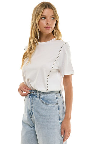 Woman wearing a white blouse with decorative buttons and light blue jeans on a white background