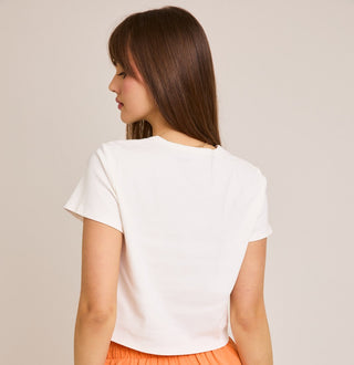 Woman wearing a white t-shirt and orange shorts on a beige background