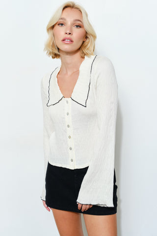 Woman wearing a white blouse with black trim and a black skirt on a white background