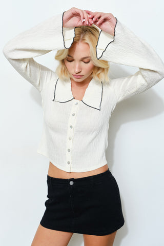 Woman wearing a white button-up shirt with black trim and a black skirt on a white background