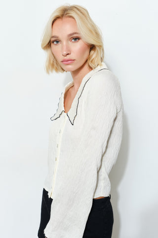 Woman wearing a light-colored blouse against a white background